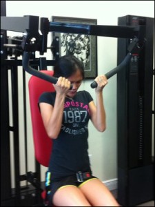 Emma performing front grip pulldowns on the MedX Torso Arm